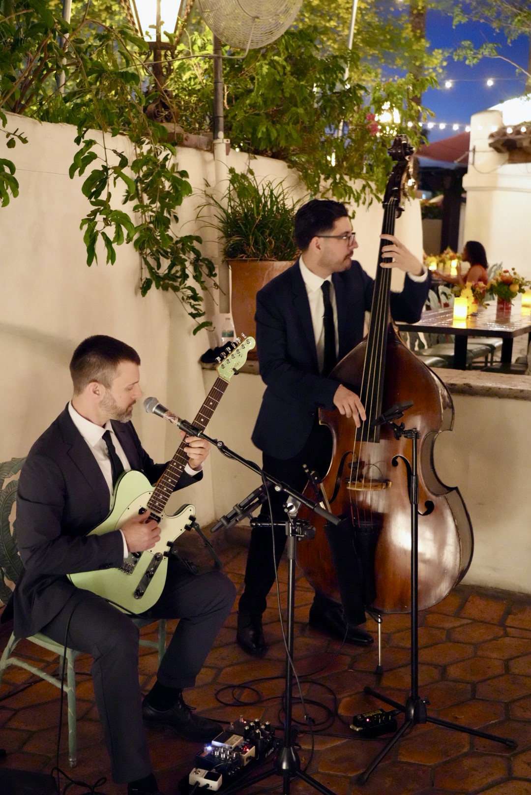 Coyah performing as a duo with an upright bassist at an evening courtyard event